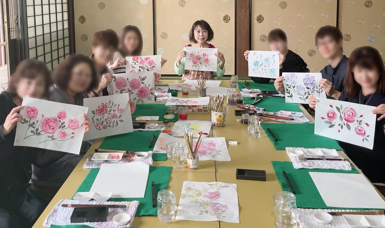 教室のようす。長机を囲んで、それぞれが描いた薔薇の絵を手に