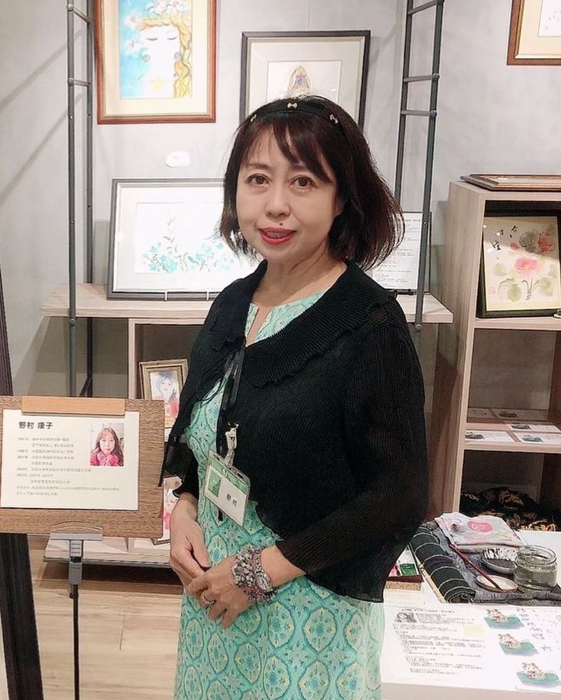 講師 野村康子。ギャラリーの作品展示の前で